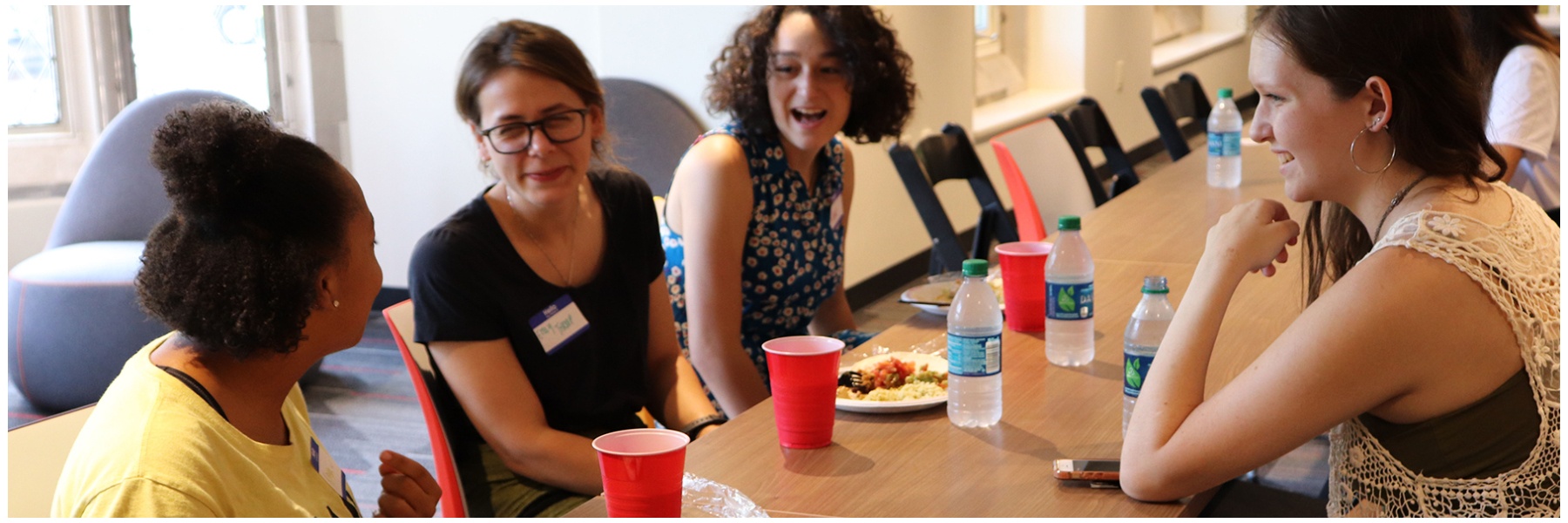 Women students and faculty chatting around a table