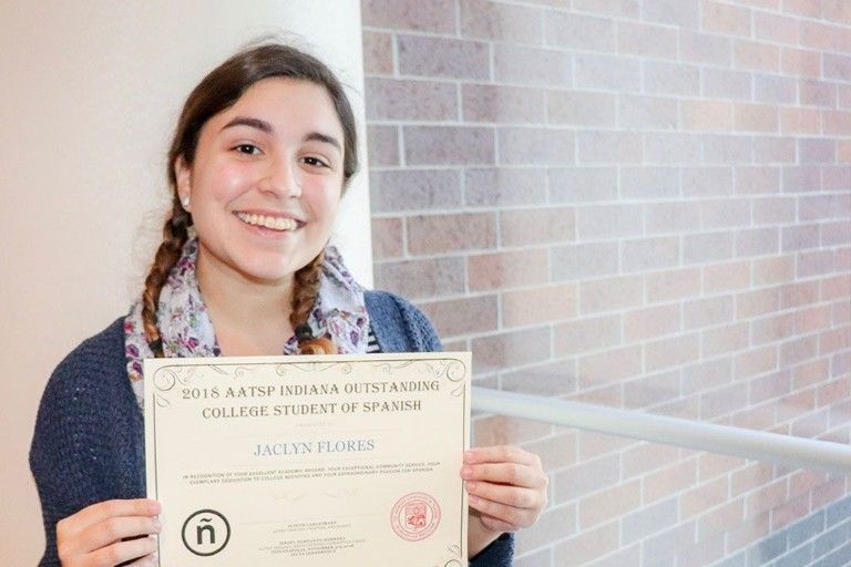 Jaclyn Flores smiling and holding up a certificate for the 2018 AATSP Indiana Outstanding College Student of Spanish