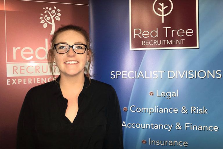 Katie Rodwell standing in front of a Red Tree Recruitment advertisement