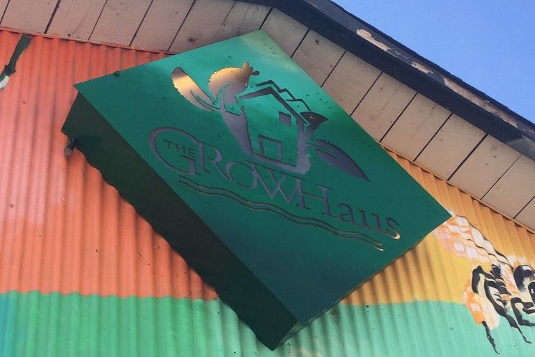 Sign for The Grow Haus with paintings of bees surrounding it